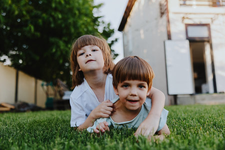 Two playful children enjoying a sunny day, laughing and exploring the lush green grass, embodying the joy of childhood innocence and friendship.の写真素材