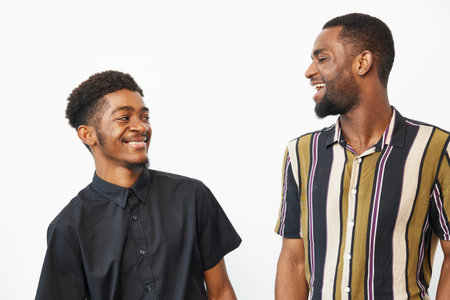 Two smiling African American men share a joyful moment. Their stylish outfits and friendly expressions create a vibrant and uplifting atmosphere that resonates with positivity.の写真素材