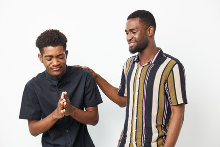 Two African American men engaging in a friendly conversation, showcasing emotions of joy and camaraderie in a bright and inviting studio setting.の写真素材