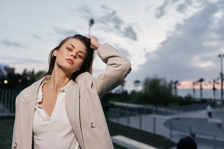 Confident businesswoman in a stylish outfit exuding professionalism against a sunset backdrop, embodying modern empowerment and elegance.の写真素材