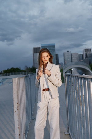 Confident business woman in a tailored outfit, showcasing professionalism against a modern urban backdrop with a dramatic sky.の写真素材