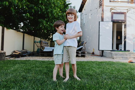 Happy children playing together outdoors in a grassy yard, showcasing friendship, joy, and carefree moments under the sun in a vibrant setting.の写真素材