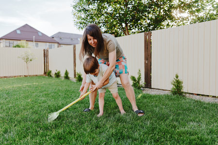 Caring woman playing with her son in the backyard, enjoying outdoor activities, surrounded by greenery and warm sunlight, creating joyful memories together.の写真素材