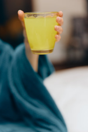 Person in blue robe holding glass and cup of lemonadeの写真素材