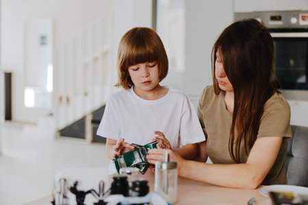 Caring woman teaching child to be responsible with money, enjoying quality time in a modern kitchen setting. A warm, educational moment that fosters learning together.の写真素材