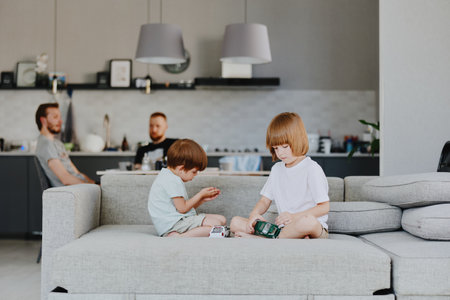 Playful children enjoying a cozy moment at home, surrounded by family. A boy and a girl sit on the sofa engaged in creative play, showcasing joy and togetherness. ###の写真素材