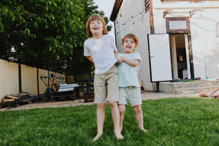 Happy children playing outdoors in a sunny backyard, enjoying summer joy and carefree moments together with laughter and fun.の写真素材