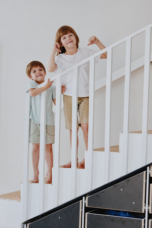 Joyful children play on the staircase, showcasing their playful personalities and vibrant energy in a bright and modern interior space.の写真素材