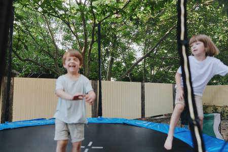 Happy children jumping on a trampoline in a sunny backyard, enjoying playful moments with joy and...