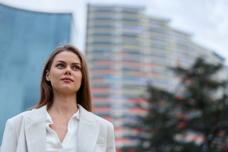 Confident woman in business attire outdoors, exuding professionalism amidst modern architecture, embodying empowerment and leadership in a corporate setting.の写真素材