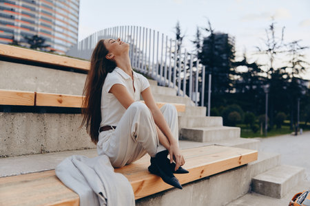 Confident businesswoman seated outdoors, showcasing modern style and serene emotions in a contemporary urban setting, emphasizing professionalism and elegance.の写真素材