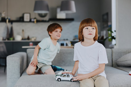 Two boys playing with toy cars in a modern living room, expressing joy and creativity, surrounded by a stylish interior design rich in natural light.の写真素材