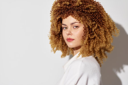 Woman with curly hair, natural beauty, soft lighting, neutral background A close up portrait showcasing confidence, elegance, and modern style in a minimalist settingの写真素材
