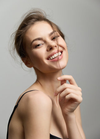 Happy young woman smiling at the camera with a playful expression, soft lighting highlighting her features. Portrait and beauty concept.の写真素材