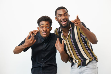 Two black men sharing a joyful moment, displaying smiles and playful gestures in a bright setting....
