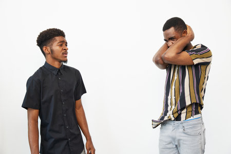 Two black men expressing various emotions against a minimalist background. One appears curious while...