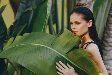 Beautiful Asian Woman Posing with Confidence and Grace in Front of Large Green Banana Leafの写真素材