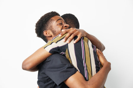 Joyful black men sharing a warm embrace, expressing friendship, trust, and comfort, captured in a...