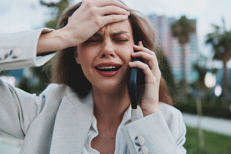 Expression of Anxiety: Young Businesswoman on the Phone in Urban Settingの写真素材