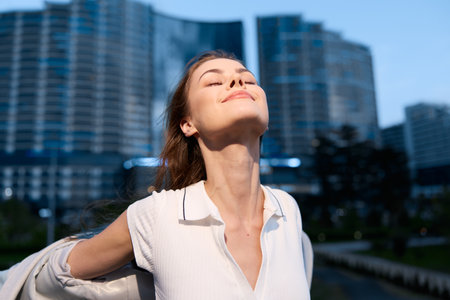 Confident businesswoman enjoying the moment in an urban setting, wearing a stylish outfit with a radiant smile, capturing empowerment and success.の写真素材
