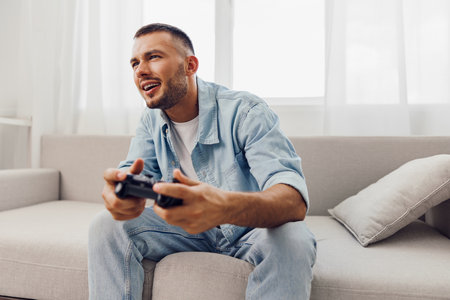 Joyful man enjoying a video game while relaxing at home, reflecting a moment of serenity and digital detox from everyday stress and work-life blur.の写真素材