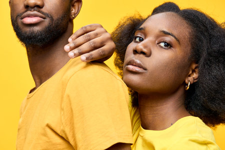 A portrait of a Black couple in matching yellow outfits against a bright yellow background, showcasing unity and confidence, ideal for themes of love and togethernessの写真素材