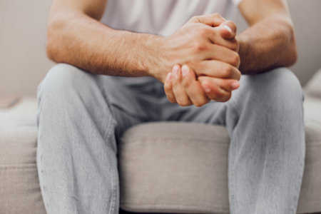 Relaxed man sitting comfortably with hands clasped, showcasing emotional strength and self-assurance in a modern interior setting. Perfect for lifestyle themes.の写真素材