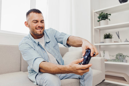 Frustrated man enjoying gaming at home, reflecting on digital detox, mental health, and the blurred line between work and personal life in todayâs tech-driven world.の写真素材