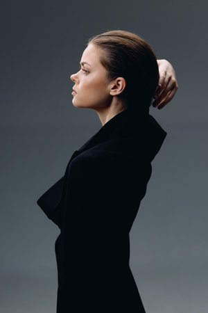 profile of a young woman dressed in black with a serious expression and a dark, minimalist background in soft lighting, emphasizing her calm and thoughtful moodの写真素材
