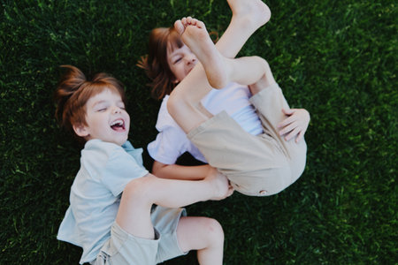 Happy children playing together on green grass, sharing laughter and joy, capturing the essence of childhood. Enjoy the vibrant summer vibes in this playful scene.の写真素材