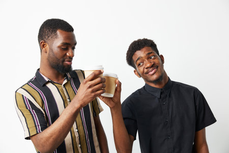 Two black men enjoying coffee together, showcasing friendship and joy. Bright colors and casual...