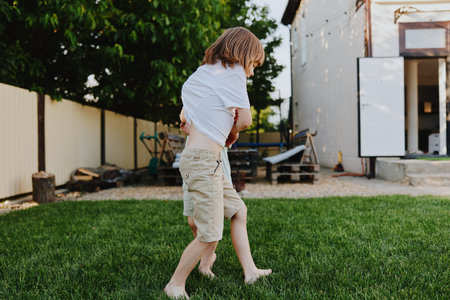 Joyful boy playing in the backyard during summer, enjoying carefree moments and laughter with...