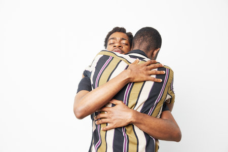 Two African American men sharing a warm and heartfelt embrace. The joy of friendship is captured in this colorful and expressive moment, showcasing connection.の写真素材