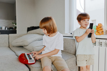 Playful children enjoying music together, creating a joyful atmosphere at home, surrounded by a cozy living space with bright colors.の写真素材