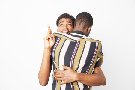 A black man showing affection to his friend, playfully sticking out his tongue. This vibrant moment...