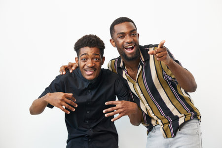 Two joyful African American men showing playful expressions and posing together, conveying happiness and friendship in a bright, clean environment.の写真素材