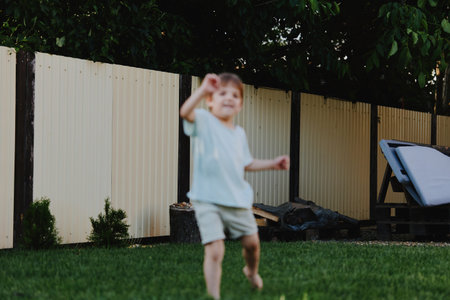 Joyful boy playing outdoors in a sunny garden, enjoying the summer atmosphere with vibrant greenery and a relaxed environment.の写真素材