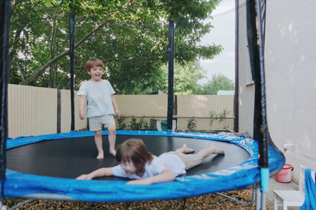 Two playful boys enjoying their time on a trampoline, showcasing joy, childhood innocence, and...