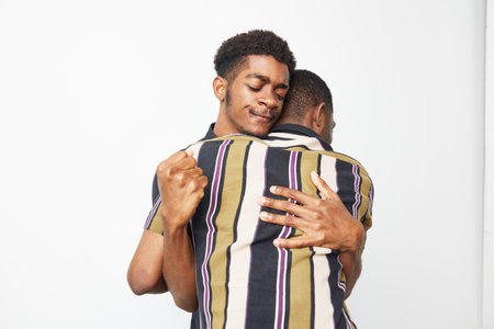 Two black men embracing each other in a warm moment, showcasing love and friendship against a clean...