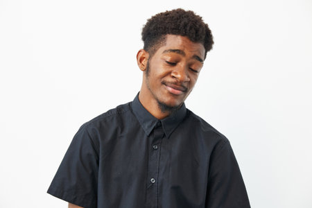 Black man with a relaxed expression, wearing a black shirt, exuding confidence and tranquility. Captivating portrait showcasing personality and style.の写真素材