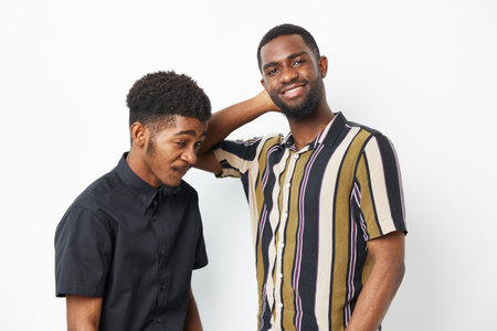 Two smiling African American men pose together, showcasing their stylish outfits and joyful expressions against a clean backdrop, highlighting friendship and camaraderie.の写真素材