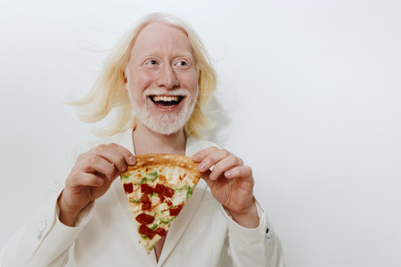 cheerful person holding a slice of pizza, smiling widely with blonde hair against a plain white background, conveying happiness and enjoyment of food in a light hearted conceptの写真素材