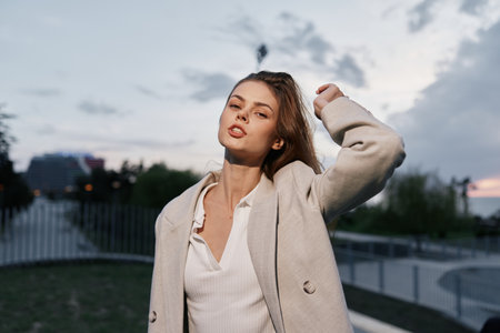 Confident businesswoman outdoors wearing a light coat, showcasing empowerment and urban style with a dramatic sky backdrop.の写真素材