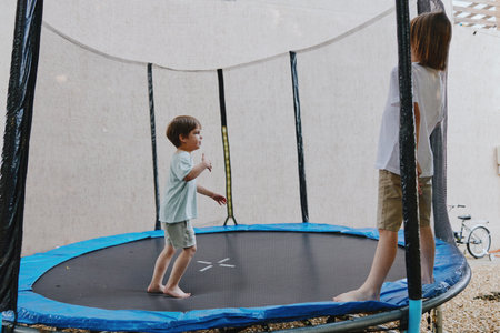 Active children playing joyfully on a trampoline, showcasing fun and excitement. The vibrant atmosphere captures the essence of childhood playtime.の写真素材