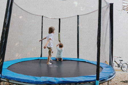 Happy children jumping on a trampoline, enjoying outdoor play in a sunny environment. Perfect for illustrating summer fun and childhood joy. ###の写真素材