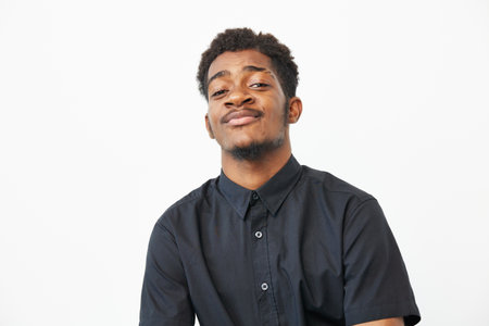 Confident black man with a charming smile against a light backdrop, showcasing his style and attitude. Ideal for representing diversity and self-expression in visuals.の写真素材