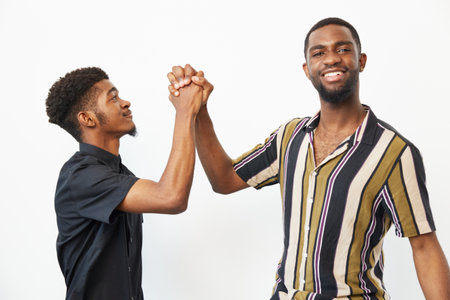 Two African American men celebrating their friendship with smiles and hand gestures, conveying joy...