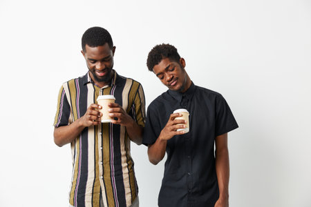 Two smiling black men enjoying coffee together, showcasing friendship and connection in a comfortable setting. Concept: warmth and joy.の写真素材