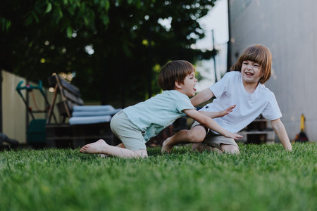 Happy children playing outdoors on green grass, enjoying a sunny day with laughter and joy. Perfect for capturing childhood moments and outdoor fun.の写真素材