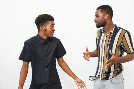 Two African American men engaging in a lively conversation, showcasing their friendship and connection in a vibrant and expressive moment filled with enthusiasm.の写真素材